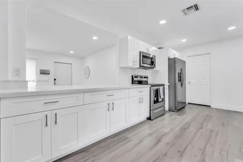 a large kitchen with stainless steel appliances granite countertop a lot of counter space and wooden floors
