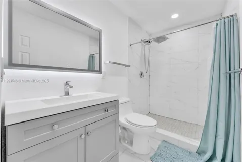 a bathroom with a shower sink vanity mirror and toilet