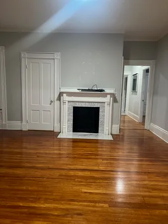 a view of kitchen and empty room with wooden floor