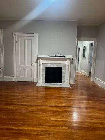 a view of kitchen and empty room with wooden floor