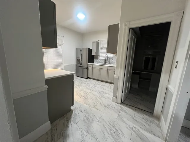 a kitchen with white cabinets and refrigerator