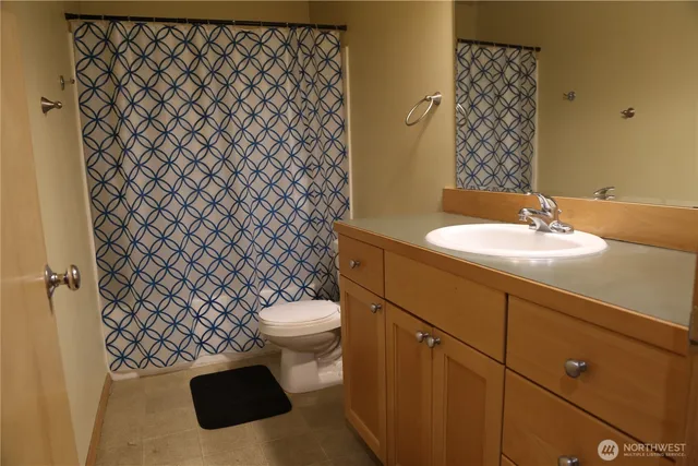 a bathroom with a granite countertop toilet and a sink