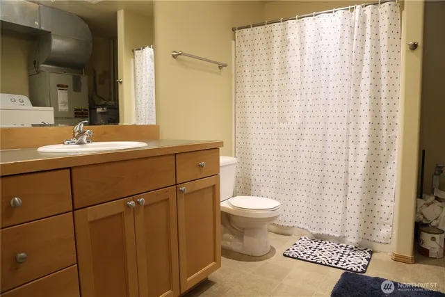 a bathroom with a sink a toilet a mirror and shower curtain