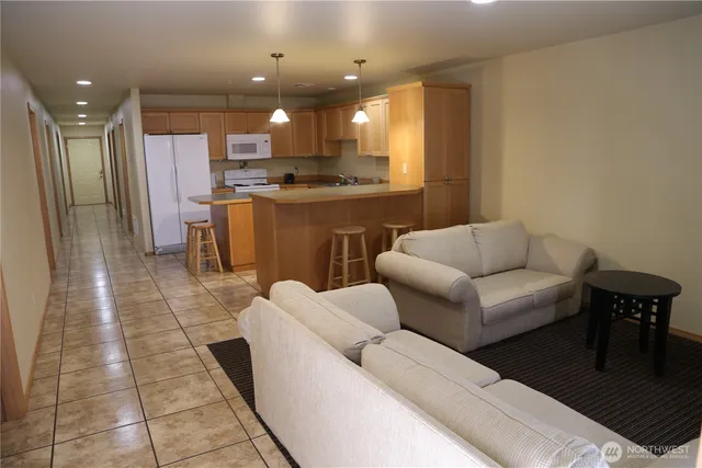 a living room with stainless steel appliances furniture a rug and a kitchen view