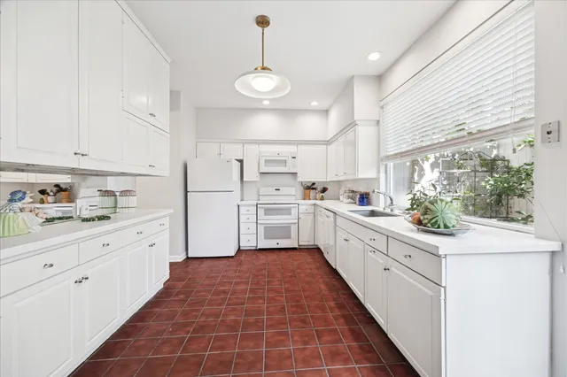 a large white kitchen with stainless steel appliances granite countertop a stove a sink and white cabinets