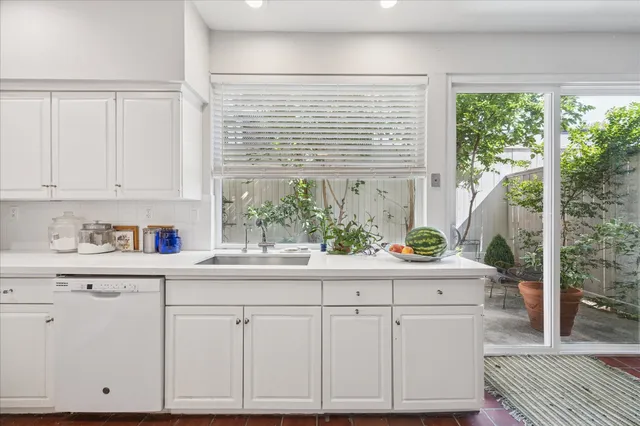 a kitchen with white cabinets and a window