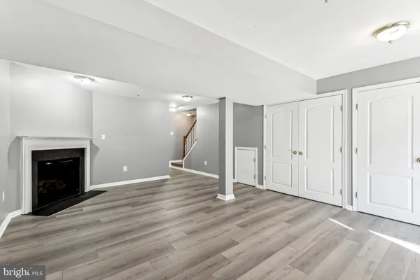 a view of an empty room with wooden floor fireplace and a window