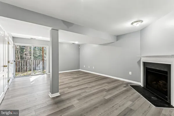 a view of an empty room with wooden floor and a fireplace