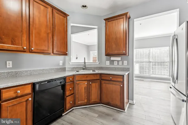a kitchen with stainless steel appliances granite countertop wooden cabinets a sink and a large window