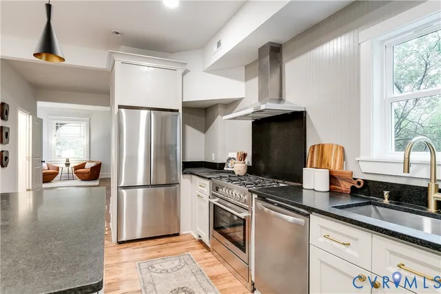 a kitchen with stainless steel appliances granite countertop a refrigerator a stove and a sink