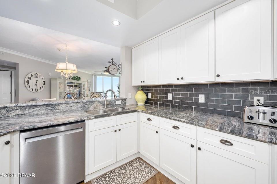 231 Riverside Drive, Unit 15071 Daytona Beach, FL 32117 - Photo 16 of 53 a kitchen with granite countertop white cabinets and white appliances