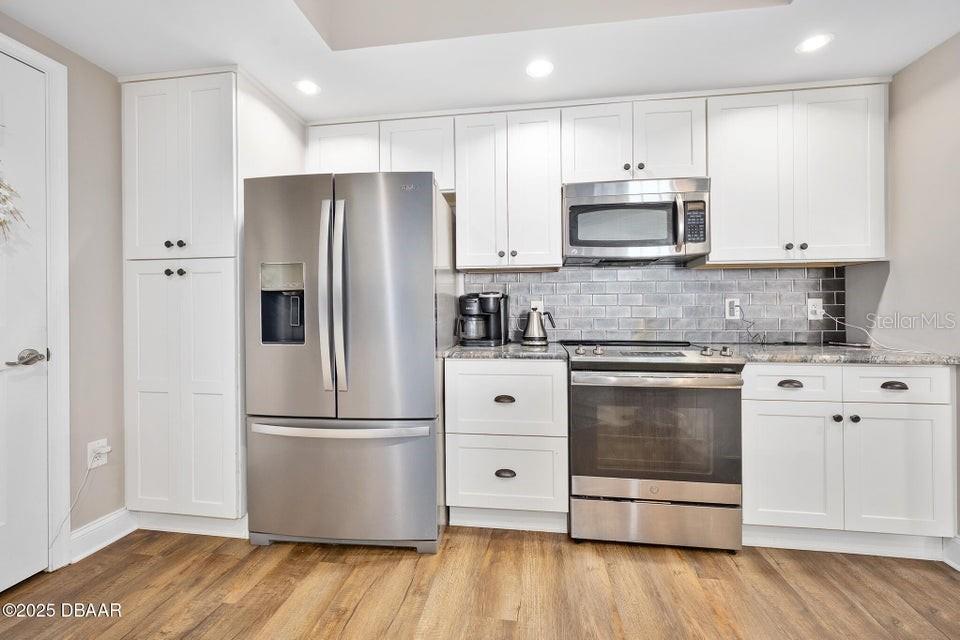 231 Riverside Drive, Unit 15071 Daytona Beach, FL 32117 - Photo 17 of 53 a kitchen with stainless steel appliances granite countertop a refrigerator microwave and white cabinets