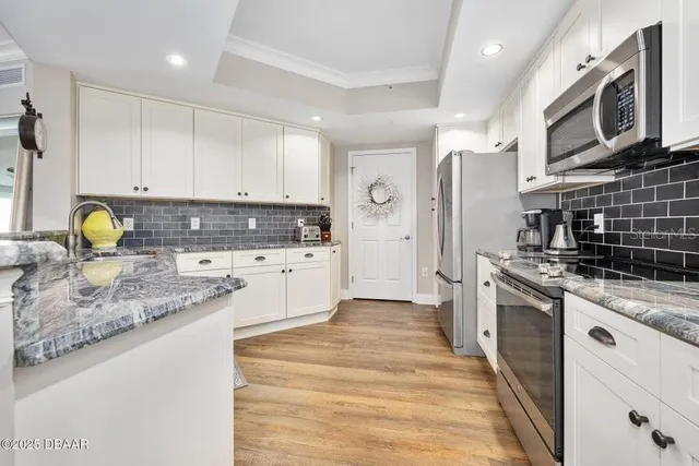 a kitchen with stainless steel appliances granite countertop a stove a refrigerator and a white cabinets