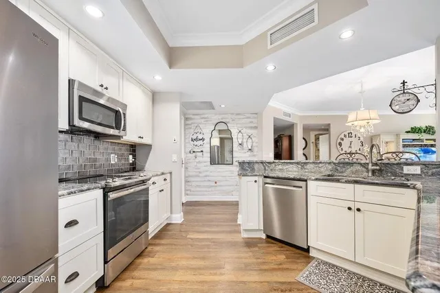 an open white kitchen with granite countertop a stove top oven microwave and cabinets