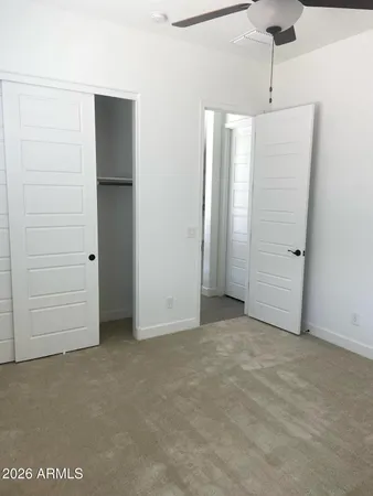an empty room with closet and a ceiling fan