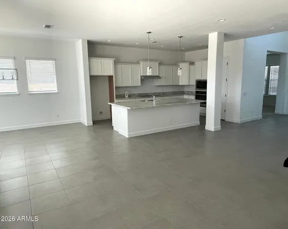 a large kitchen with a large counter top space a sink stainless steel appliances and cabinets