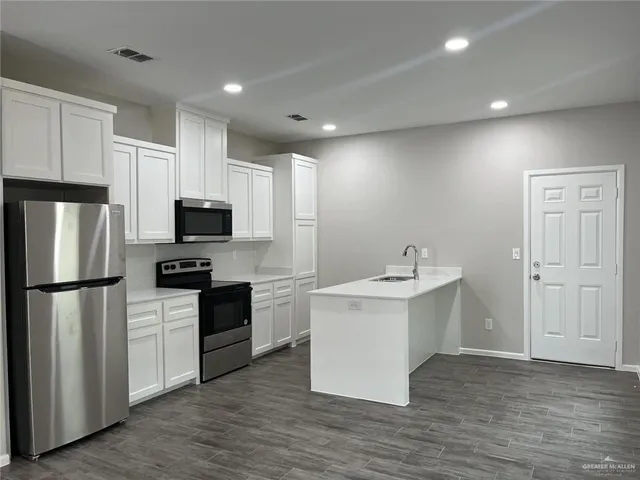 a kitchen with white cabinets stainless steel appliances and sink