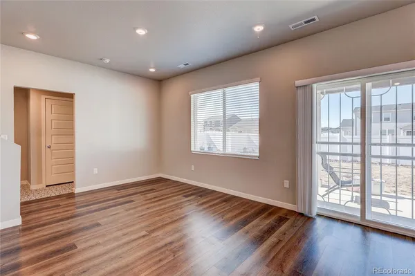 a view of an empty room with wooden floor and a window