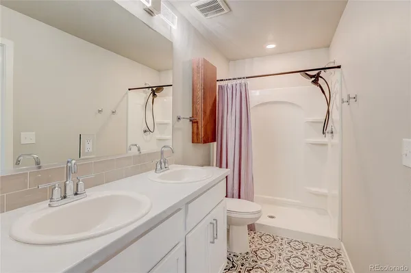 a bathroom with a granite countertop sink a toilet and shower