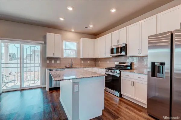 a kitchen with stainless steel appliances granite countertop a refrigerator a stove top oven a sink and dishwasher with wooden floor