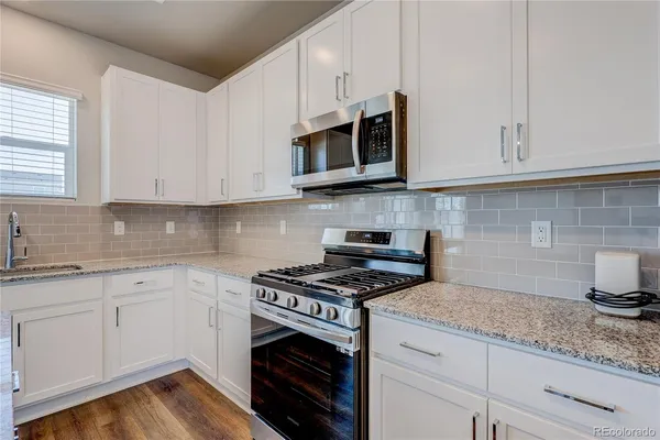 a kitchen with stainless steel appliances granite countertop a sink a stove and microwave