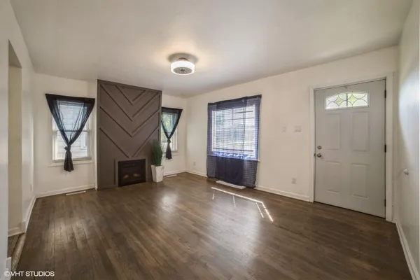 an empty room with wooden floor fireplace and windows