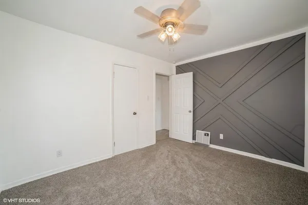 an empty room with a chandelier fan and closet