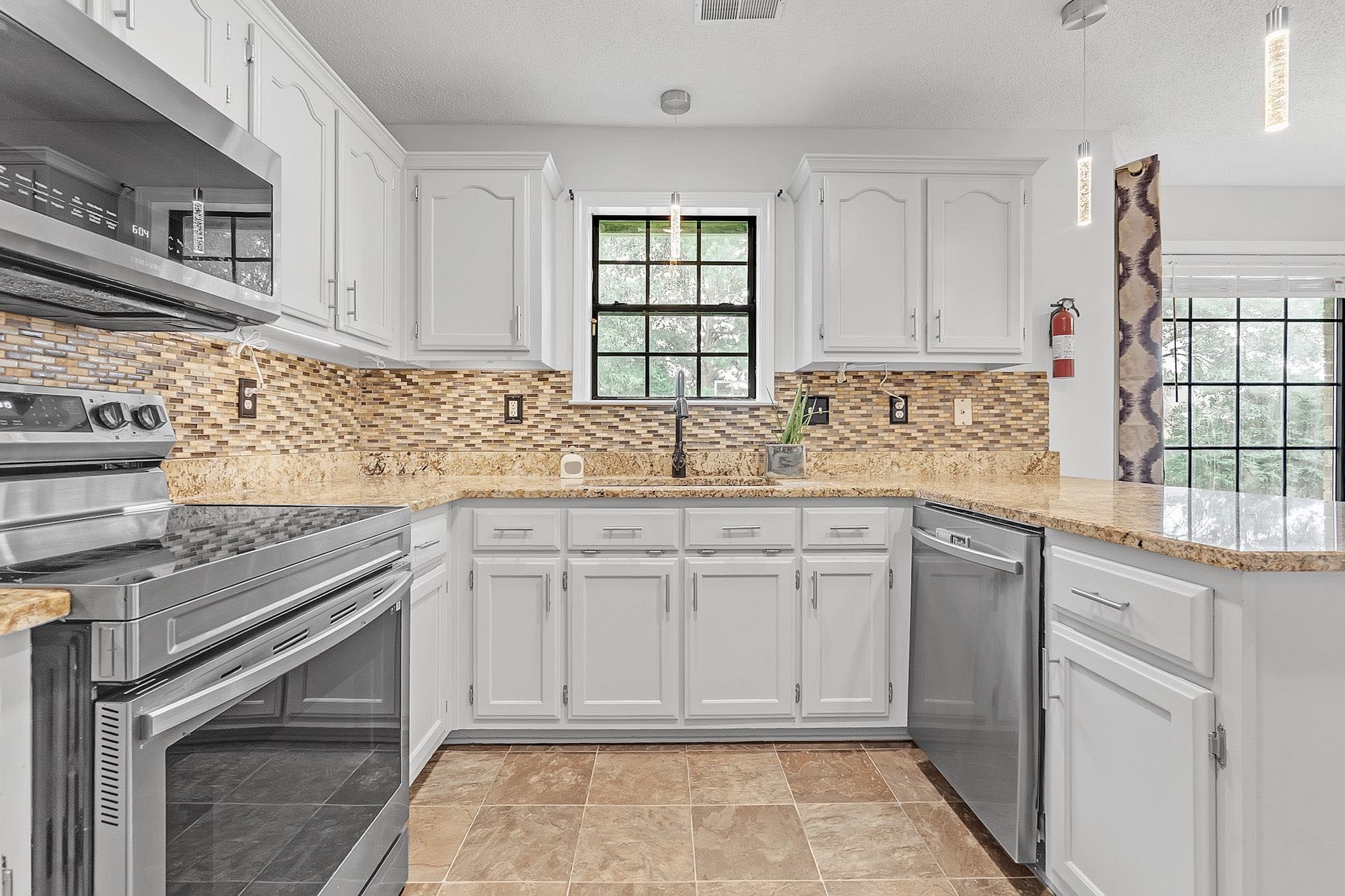 4788 Shadow View Lane Bartlett, TN 38002 - Photo 11 of 33 Kitchen with appliances with stainless steel finishes, a sink, white cabinets, a peninsula, and light stone countertops
