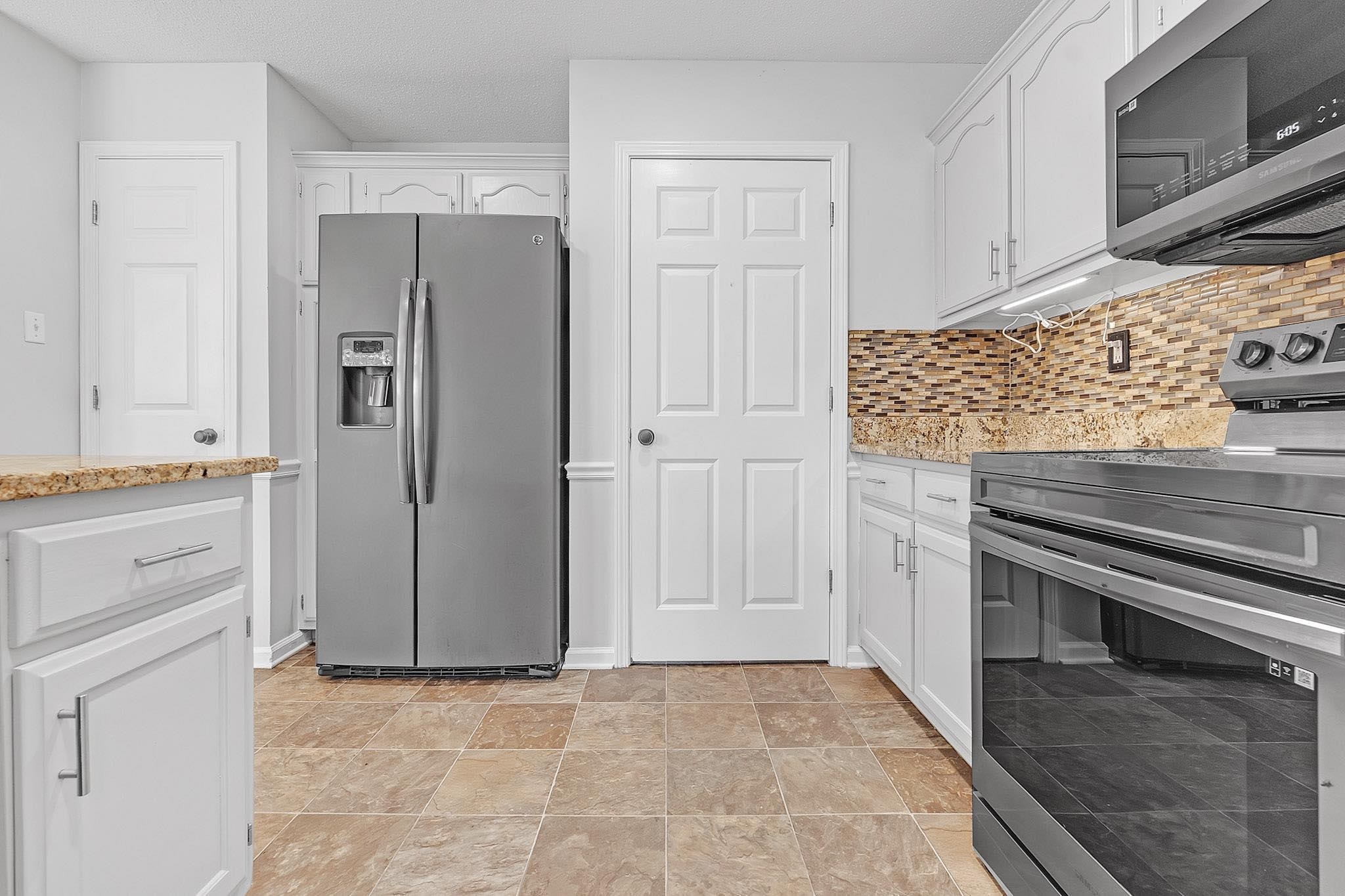 4788 Shadow View Lane Bartlett, TN 38002 - Photo 13 of 33 Kitchen with appliances with stainless steel finishes, white cabinets, backsplash, and light stone finish floors