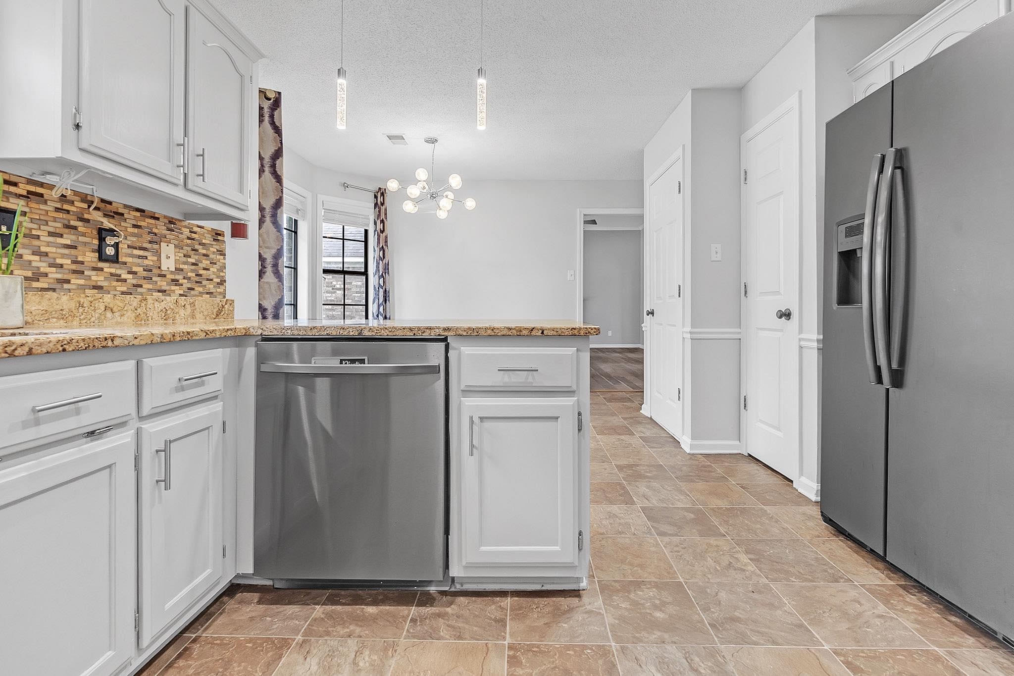 4788 Shadow View Lane Bartlett, TN 38002 - Photo 15 of 33 Kitchen with stainless steel appliances, a chandelier, decorative backsplash, a peninsula, and light stone finish floors