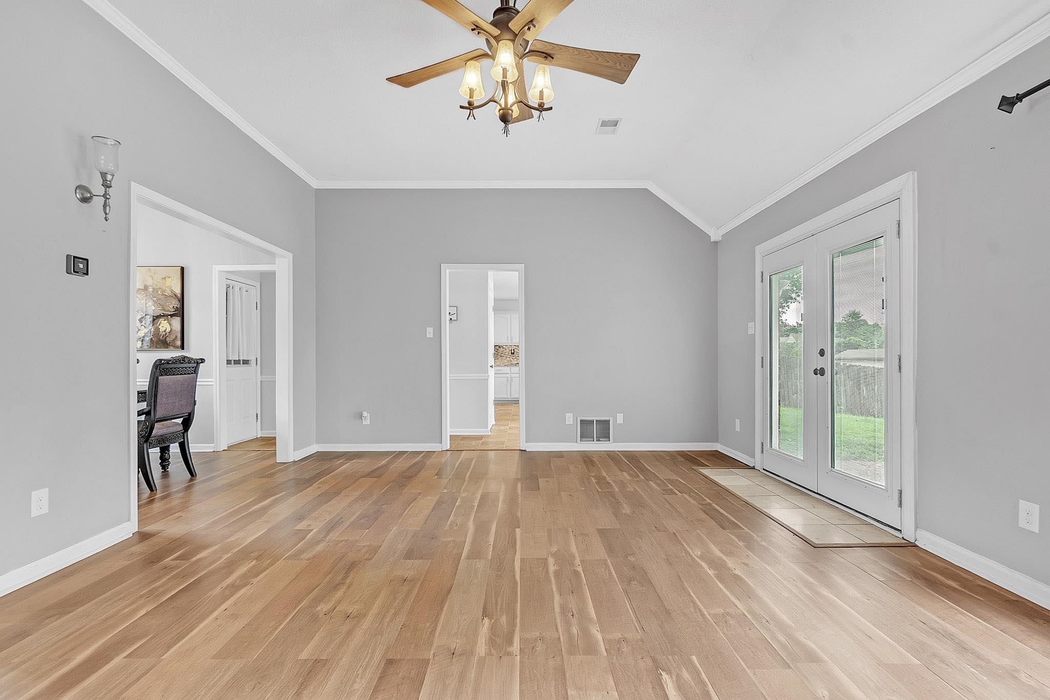 4788 Shadow View Lane Bartlett, TN 38002 - Photo 7 of 33 Unfurnished living room featuring light wood-style floors, ceiling fan, crown molding, lofted ceiling, and baseboards