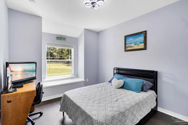 a view of a room that has a bed and wooden floor
