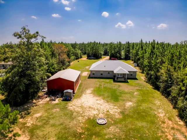 an aerial view of residential house with outdoor space and trees all around