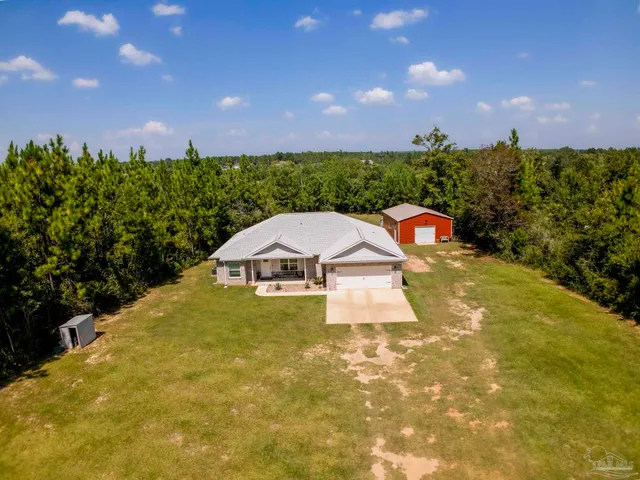 an aerial view of residential houses with outdoor space and trees
