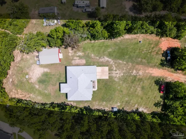 an aerial view of residential houses with outdoor space and trees