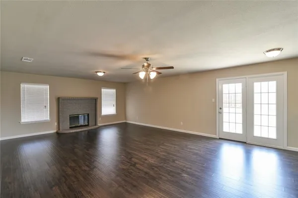 an empty room with wooden floor fireplace and windows