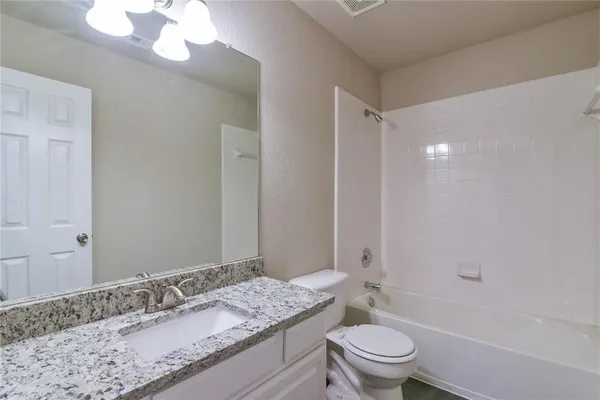 a bathroom with a granite countertop sink a toilet and a mirror