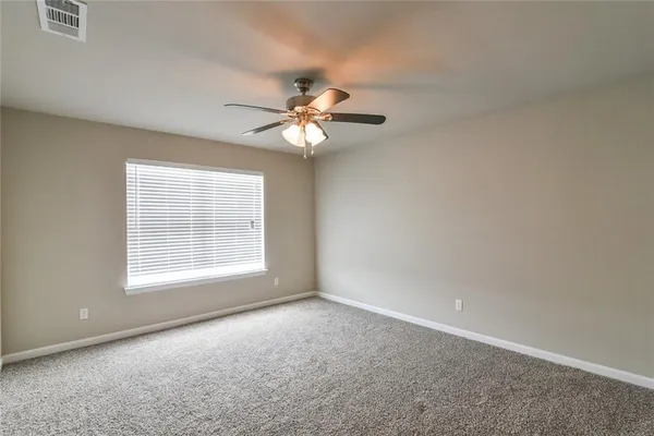 an empty room with chandelier fan and windows