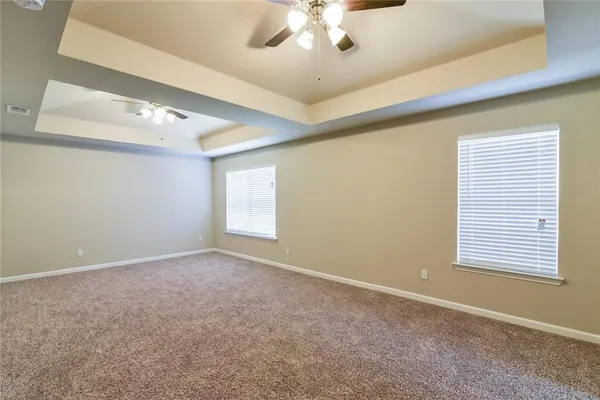 en empty room with windows and ceiling fan