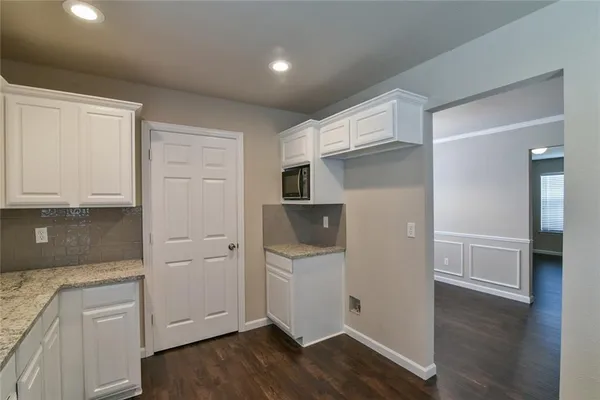 an empty room with wooden floor and cabinet