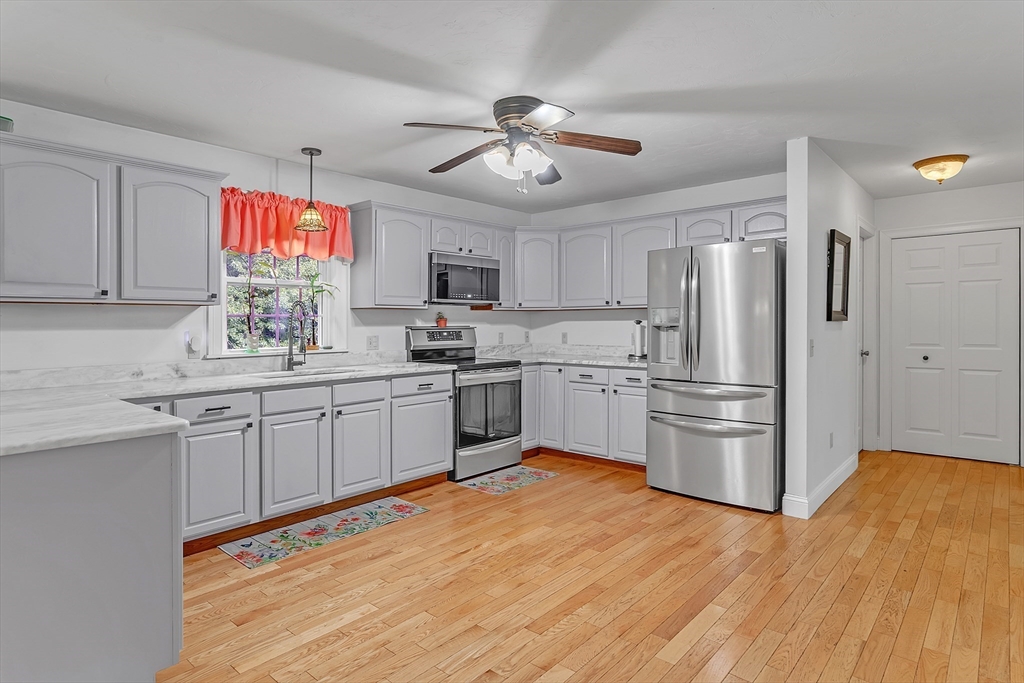 185 Bemis Road Warren, MA 01585 - Photo 4 of 36 a kitchen with granite countertop a refrigerator oven a sink dishwasher and white cabinets with wooden floor