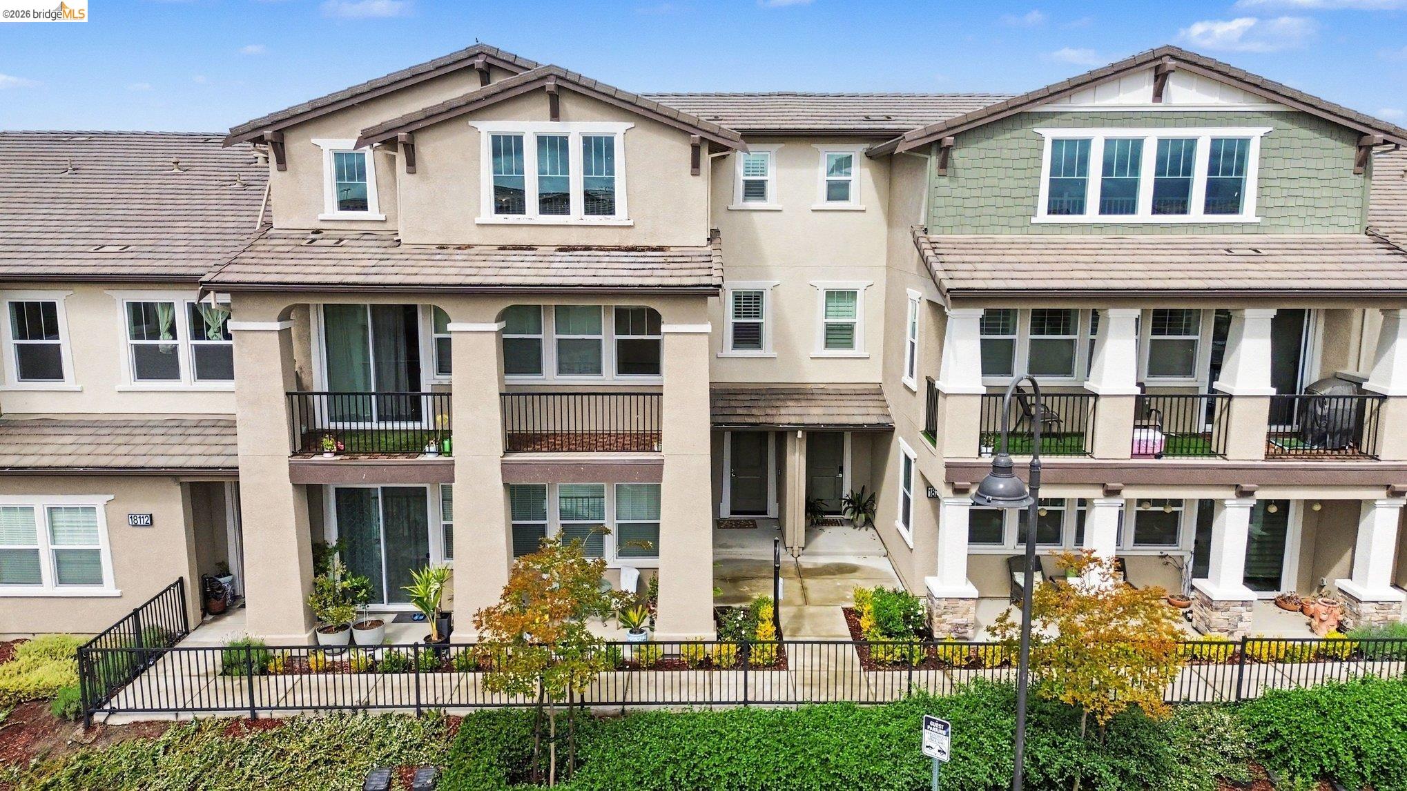 18210 Argento Loop San Ramon, CA 94583 - Photo 41 of 44 Multi-level townhouse exterior featuring stucco siding with shake accents, multiple balconies with black railings, and a fenced front patio area