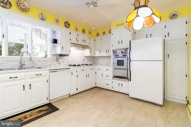 a kitchen with stainless steel appliances a white cabinet and a chandelier