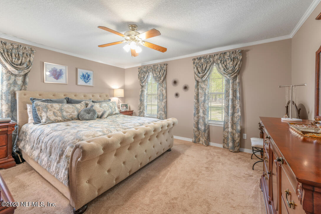 37491 Poole Road Hilliard, FL 32046 - Photo 27 of 39 a spacious bedroom with a bed and a chandelier