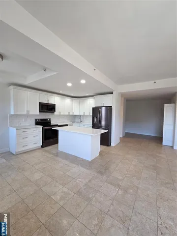a large kitchen with stainless steel appliances granite countertop a refrigerator and a stove top oven