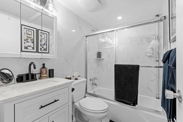 a bathroom with a shower sink vanity mirror and toilet