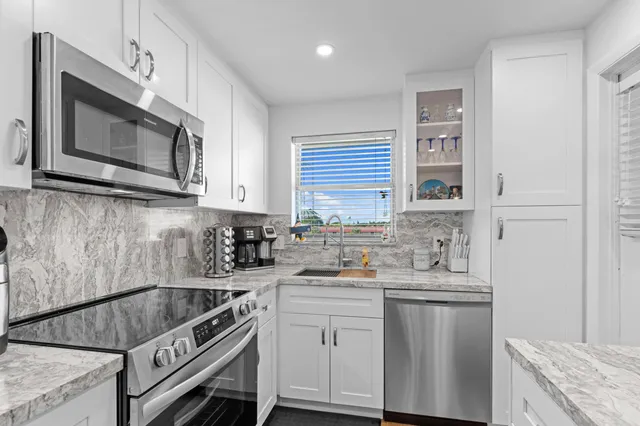 a kitchen with stainless steel appliances white cabinets and a stove top oven