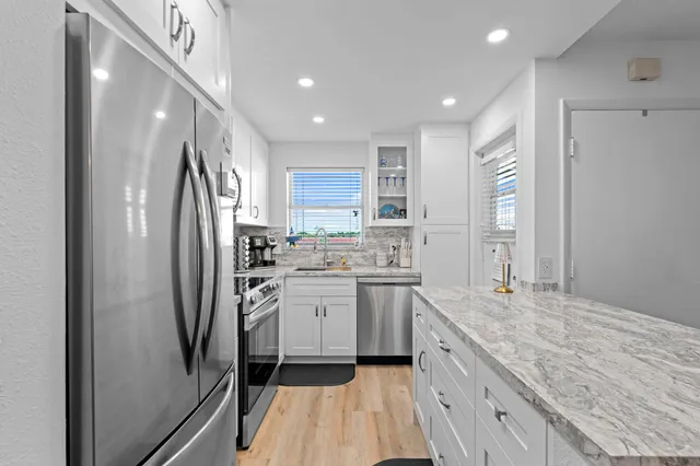 a kitchen with stainless steel appliances granite countertop a refrigerator and a sink