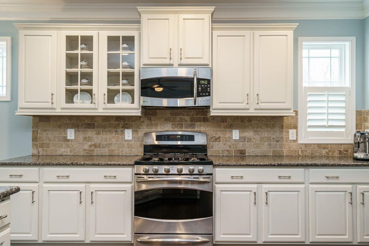 5602 Wade Park Boulevard Raleigh, NC 27607 - Photo 17 of 34 Upgraded cabinets, glass front cabinets, stainless appliances, five burner gas range, stone subway backsplash, granite and refrigerator included in this chef's kitchen! Kitchen