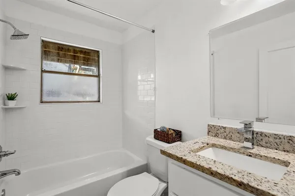 a bathroom with a granite countertop sink mirror toilet and bathtub